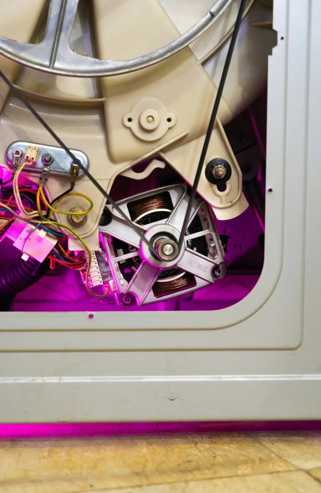 Rear panel removed from a washer, showing the drive motor, belt, and wiring