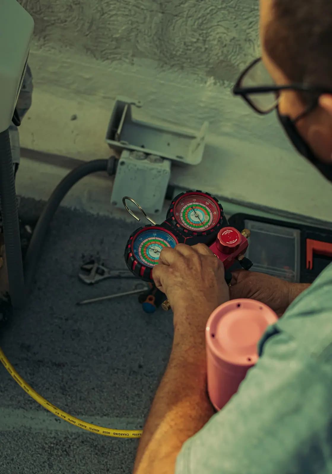 Technician's hands adjusting a refrigerant manifold gauge set